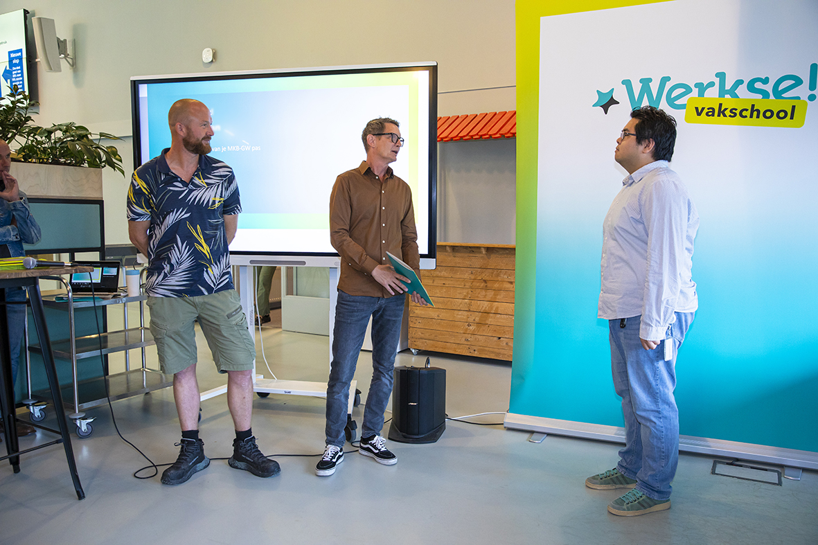 Mannelijke cursist wordt toegesproken door twee begeleiders