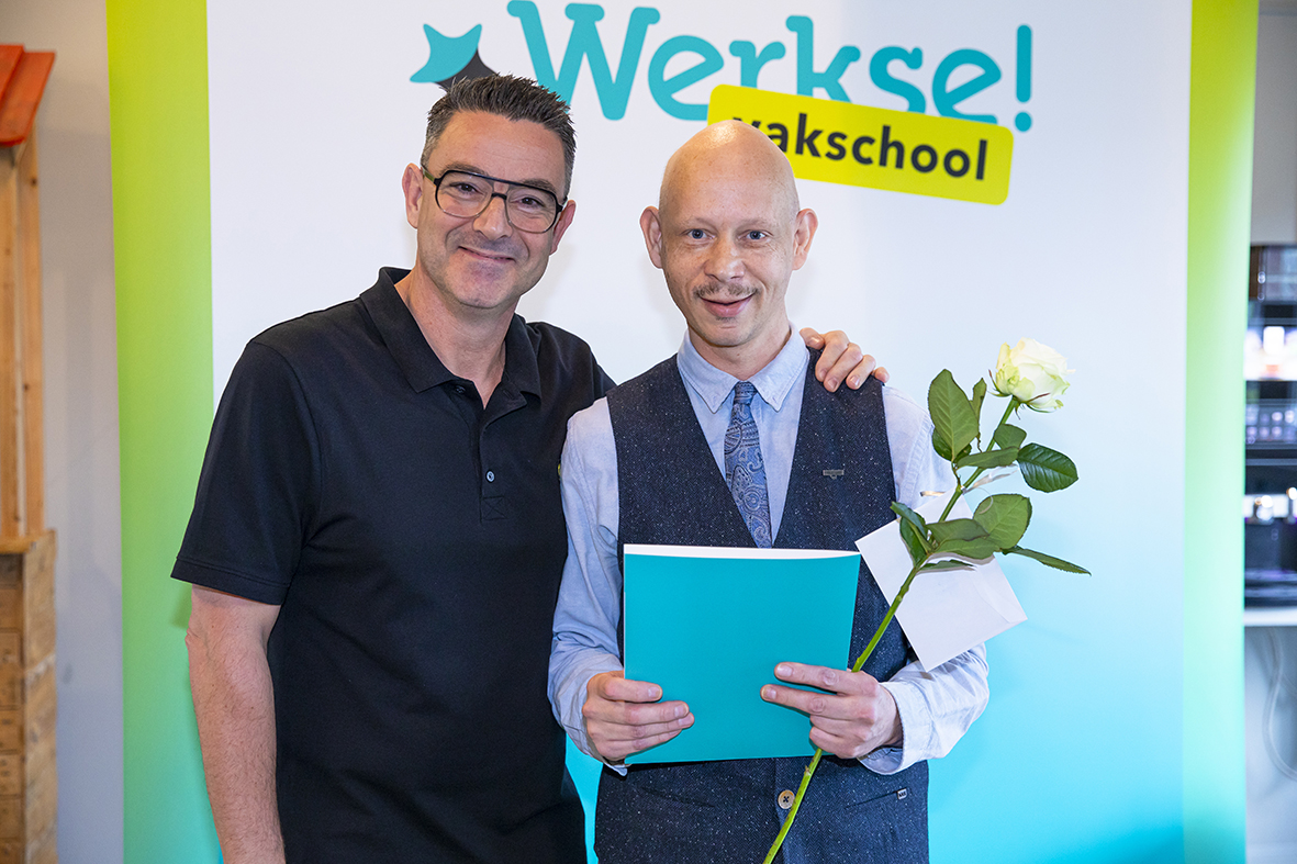 Begeleider en cursist op de foto. Cursist met certificaat en bloem in de hand.