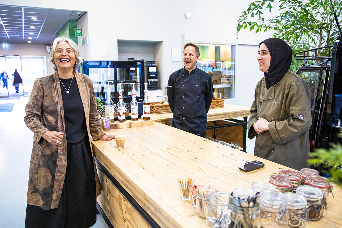 Catering medewerkers lachend met de wethouder bij de barista uitgifte