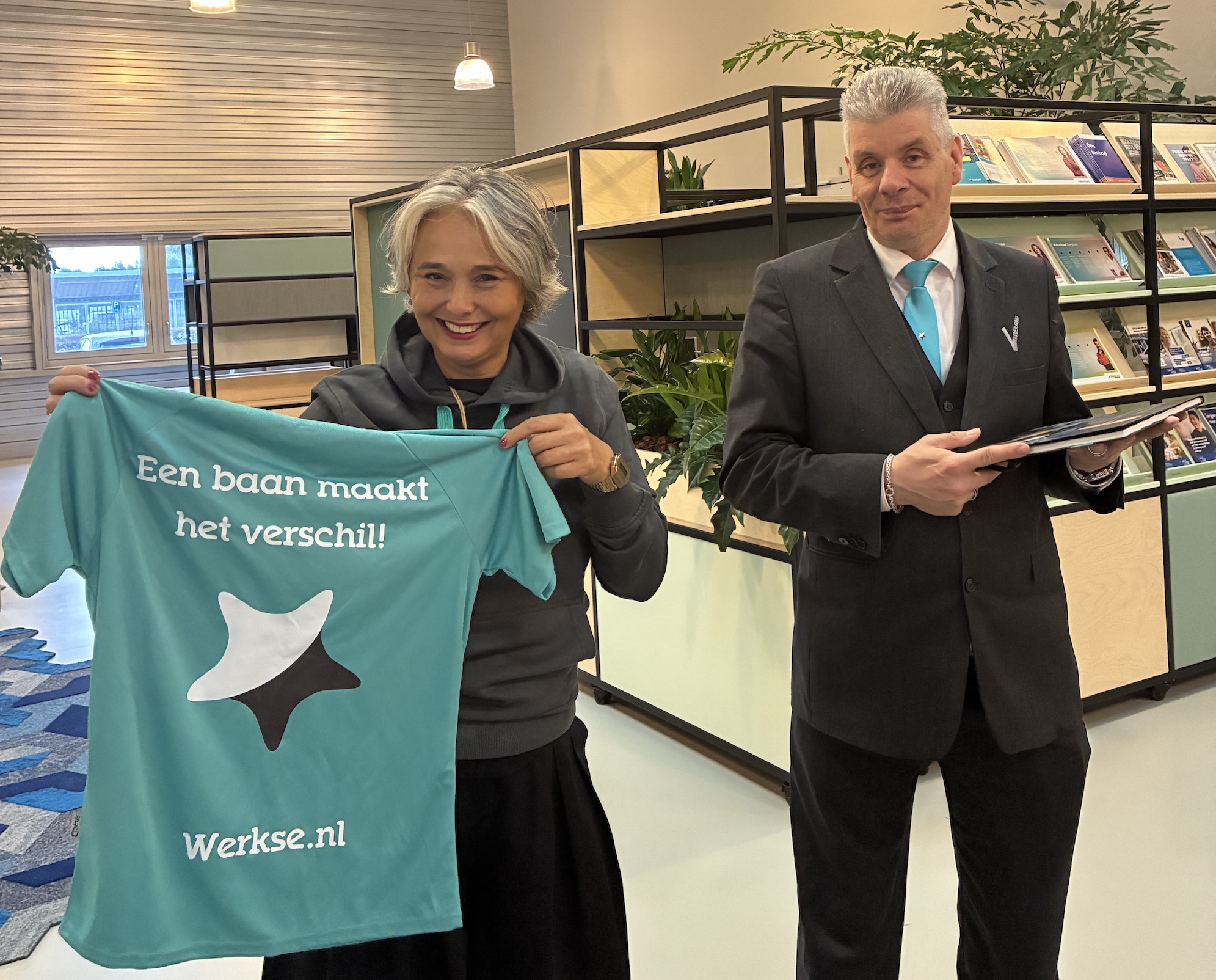 Beveiligingsmedewerker overhandigd een Werkse! t-shirt aan Wethouder Hélène Oppatja