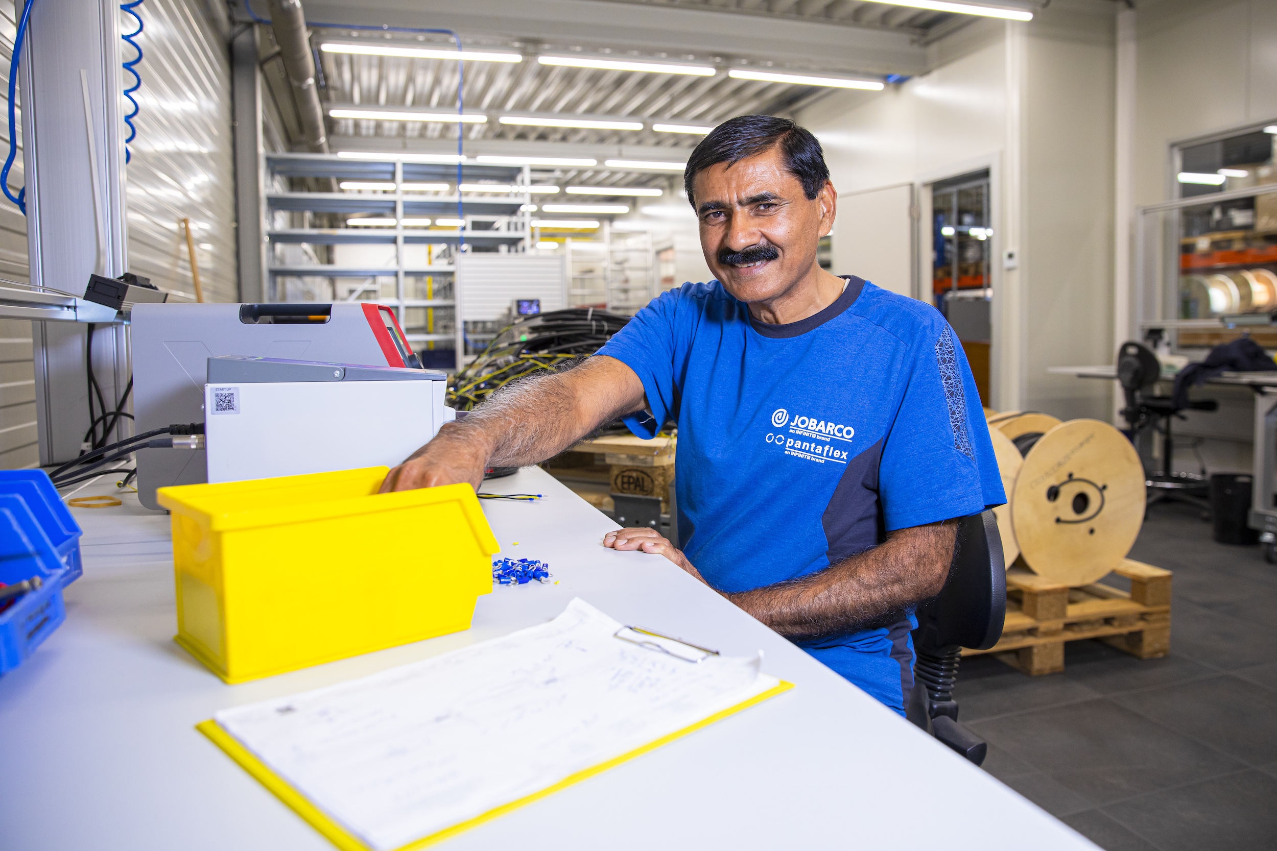 Ali bij Jobarco zittend op zijn werkplek waar hij zaken assembleert